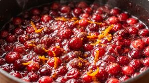 Ultra close-up macro of bubbling ruby red fresh cranberry orange sauce simmering in saucepan